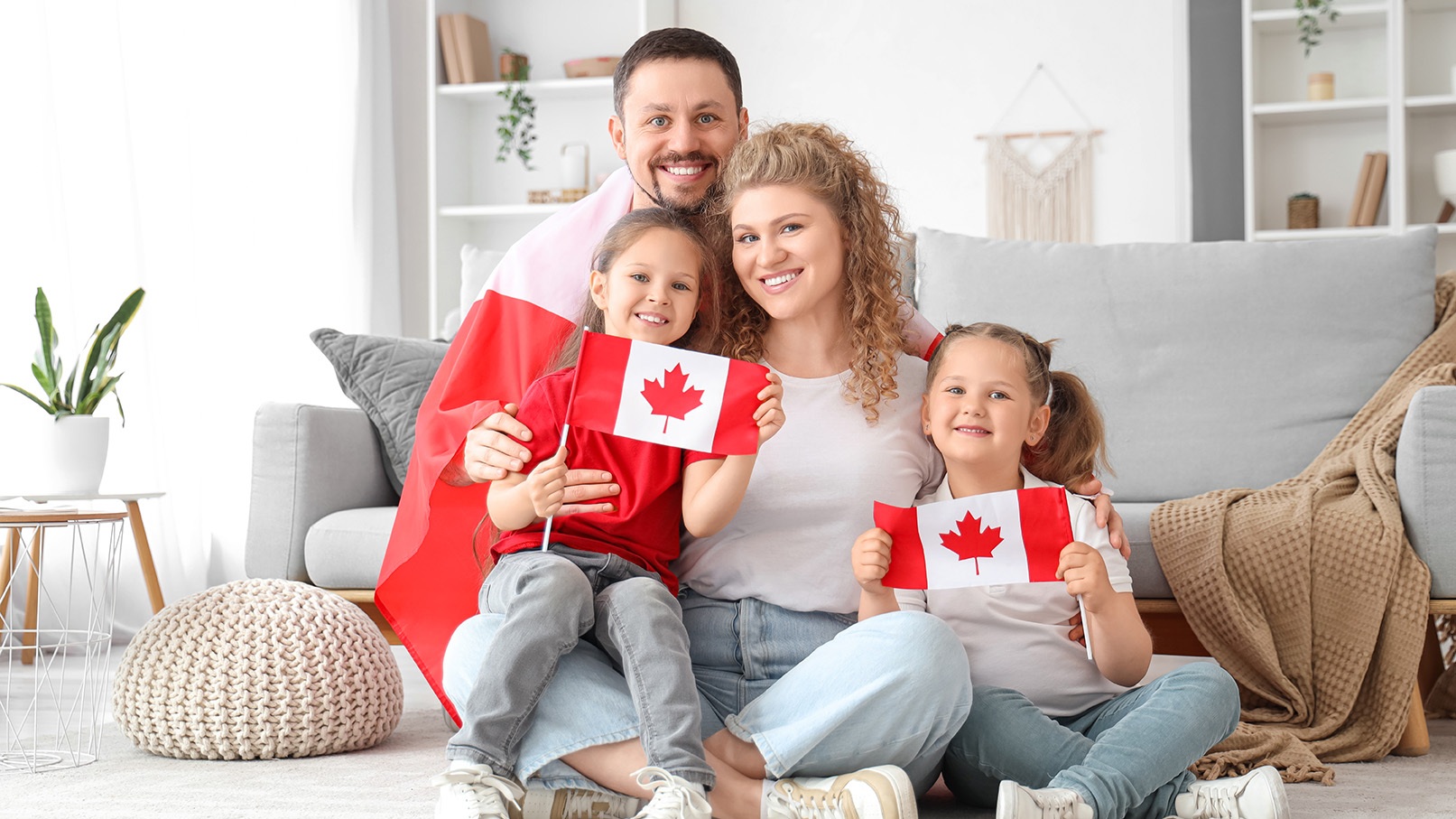 A happy family holding Canadian flags