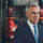 Prime Minister Mark Carney in a dark suit and blue tie, photographed in front of industrial pipefitting equipment at a Calgary union training facility.